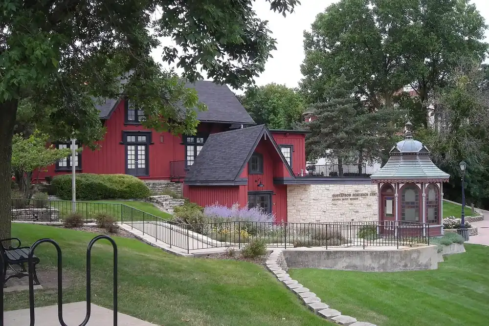 Red historic railroad depot museum and gazebo on a green lawn in Batavia, Illinois