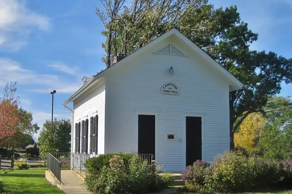 Small white clapboard Campton Town Hall among trees under a blue sky, Illinois