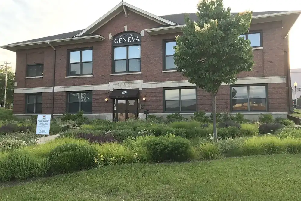 Brick Geneva City Hall behind a planted garden on a summer evening, Illinois