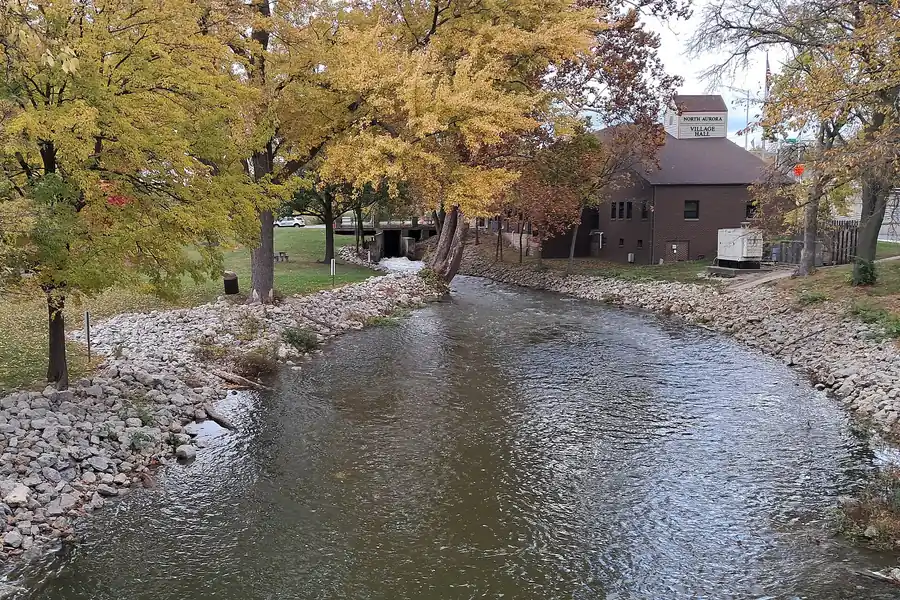 Stream through Riverfront Park with autumn trees near the village hall, North Aurora