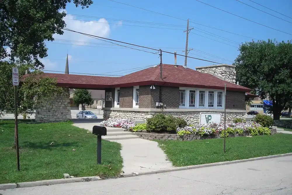 Brick and stone Ardmore Avenue train station with flower beds in Villa Park