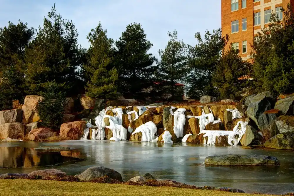Rock waterfall and pond framed by evergreen trees in Wheeling, Illinois